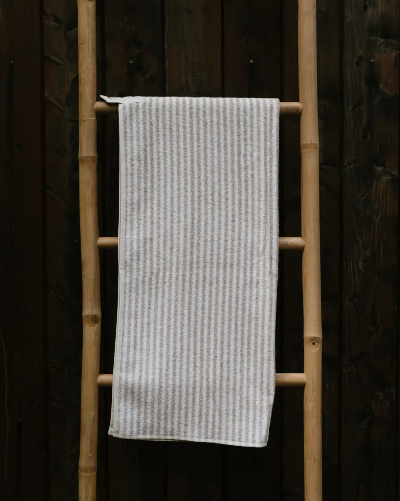 Lniany ręcznik do sauny frotte striped w paski wisi na drabince.
