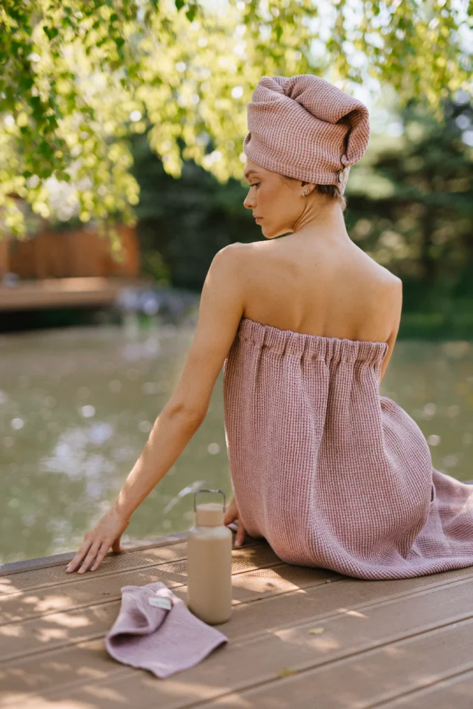 kobieta po saunowaniu ubrana w lniany turban wafel i naturalne lniane pareo do sauny