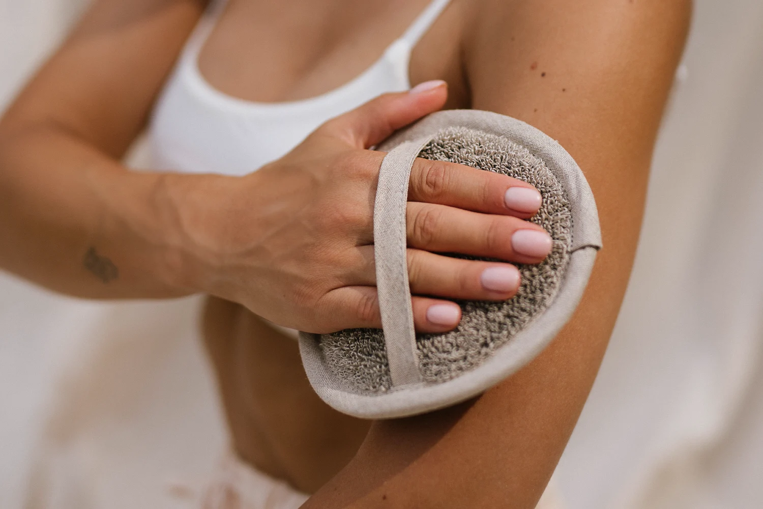 kobieta peelingująca skórę krążkiem podczas przerwy w sensie saunowania